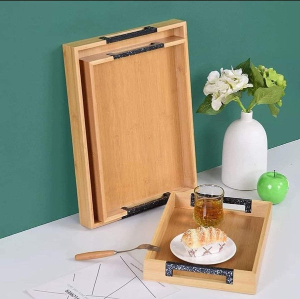 3-piece bamboo tray set showcasing two trays standing against the wall with a small tray holding a glass of drink and a plate of dessert. Ideal for serving appetizers, drinks, and desserts.