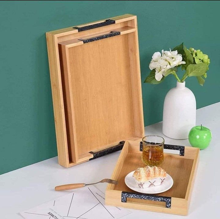 3-piece bamboo tray set showcasing two trays standing against the wall with a small tray holding a glass of drink and a plate of dessert. Ideal for serving appetizers, drinks, and desserts.