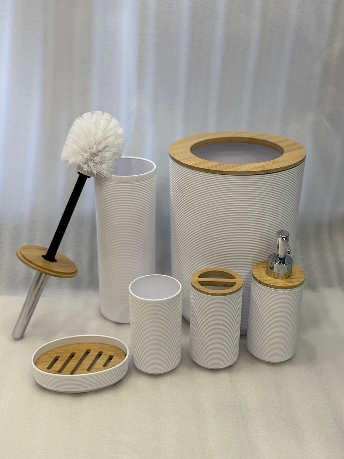 Bathroom accessories set with white containers, wooden accents, and a brush on a neutral background