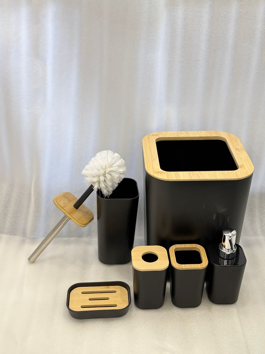 Bathroom accessories including a black trash can, soap dispenser, and other items on a marble surface.