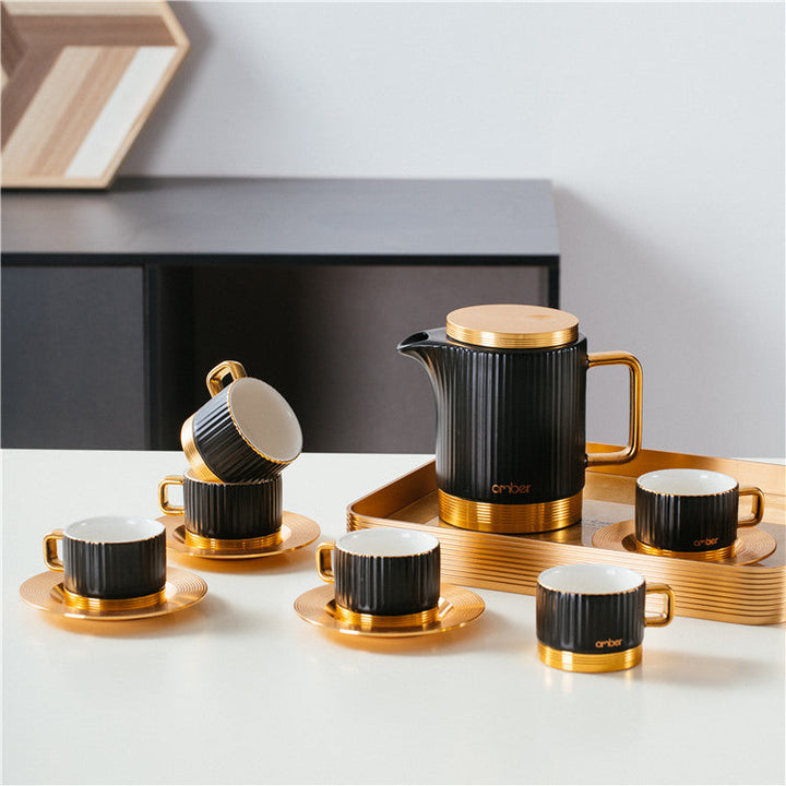 Black ceramic coffee pot and cup with gold handles and metallic tray. The top 75% of the pot and cup are black, and the bottom 25% is gold, showcasing a luxurious two-tone design with matching gold saucers.