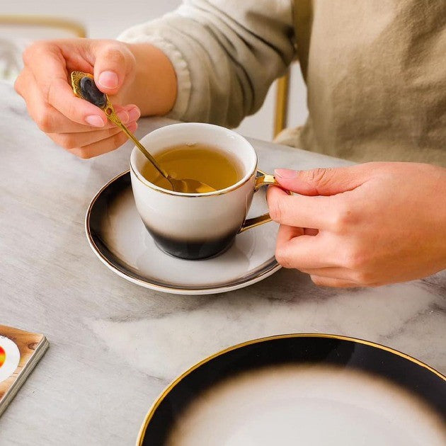 Chai Time in Style – Black & White Tea Cup with Saucer and Spoon, Filled with Tea