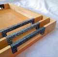 Close-up of metal handles on the bamboo serving trays