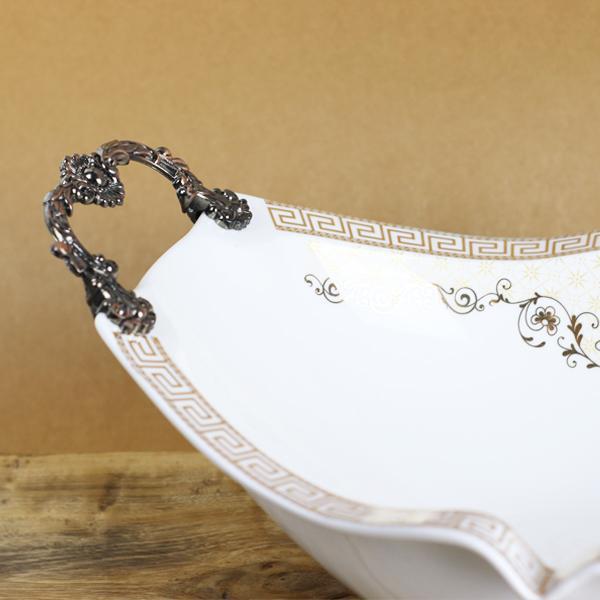 Oval-shaped ceramic bowl with a white base and black intricate Versace-inspired design, elegantly displayed.