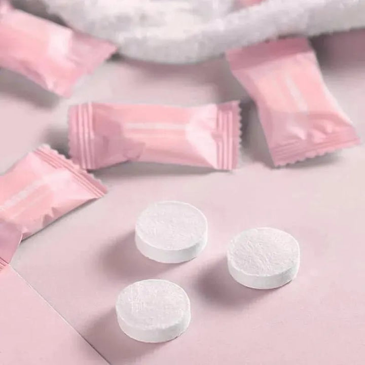 Close-up view of the disposable compressed towel packaging resembling candy, alongside an expanded towel in tablet form on a white background.