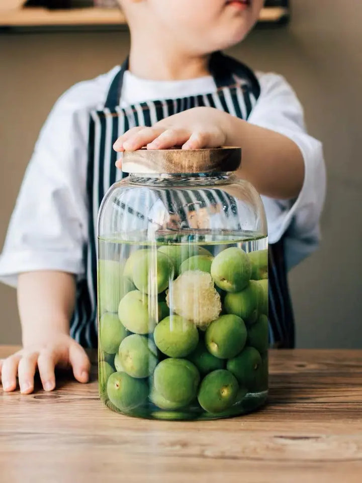 Different angle of 3000ml glass jar filled with olives and water, with a child’s hands gently holding the jar, demonstrating ease of use.