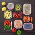 Four sizes of HaulJunction food containers, two of each size, filled with fresh food, all sealed with airtight lids and viewed from the top for easy storage.