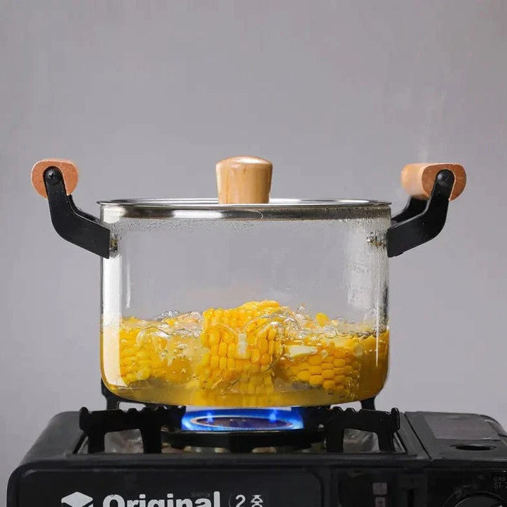 Glass cooking pot on a gas stove boiling corn, showcasing its heat-resistant quality.