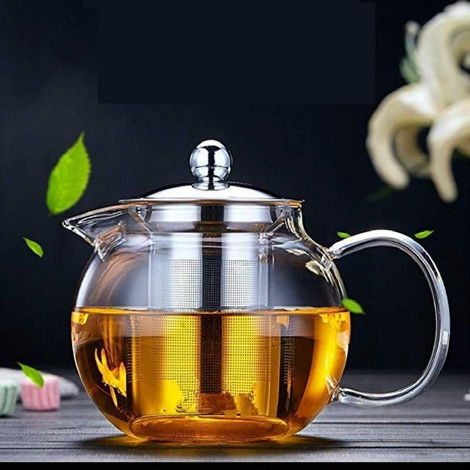 Glass teapot filled with freshly brewed tea placed on a tabletop, showcasing its elegant design.