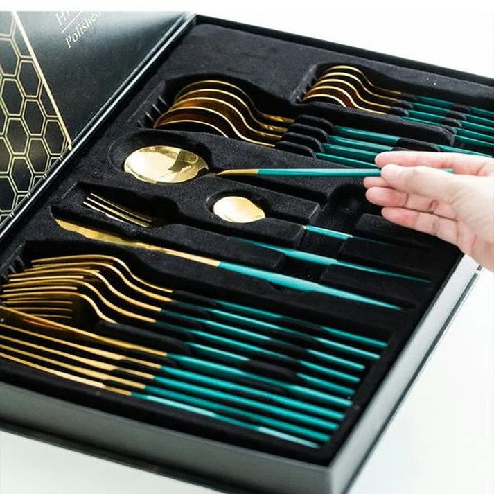 Gold and green handle flatware set displayed in open box packaging, showcasing all 24 pieces neatly arranged.