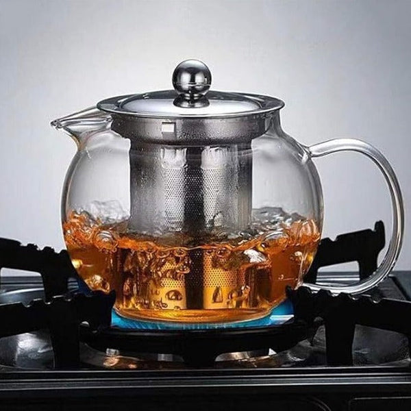 Heat-resistant glass teapot with infuser on a gas stove, brewing tea with boiling water.