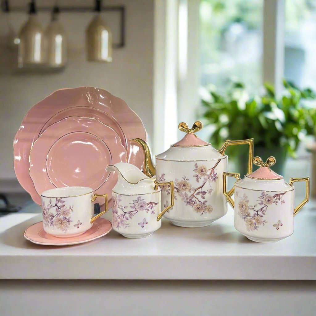 Modern ceramic floral teaset featuring pink plates and white mugs and pots with pink lids. The set boasts an elegant design perfect for tea settings.