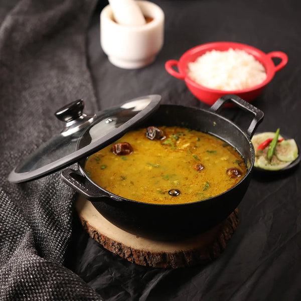 Non-stick pot on a wooden dish with curry and the lid placed on its side, showcasing its practical design.