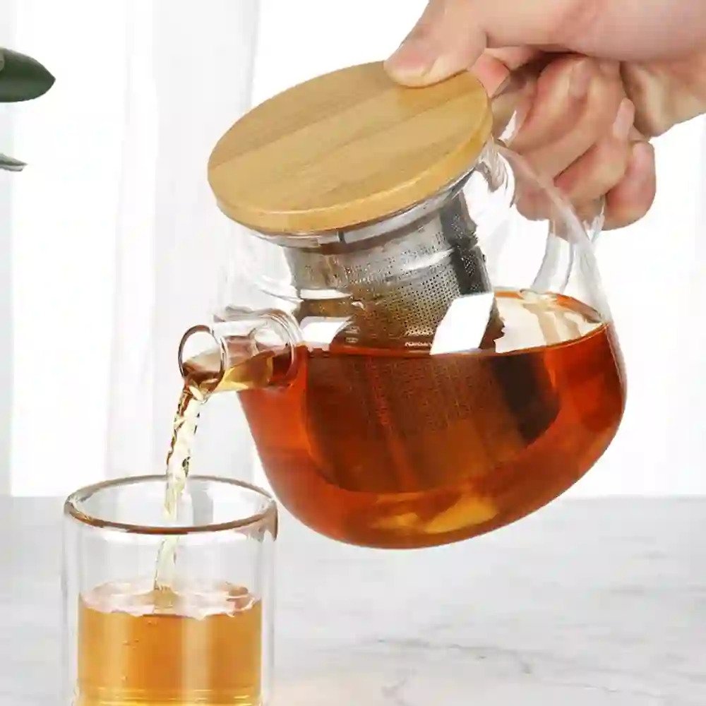 Complete 6-piece glass kettle teapot set displayed on its wooden tray, featuring a half-filled kettle with visible mesh, and 4 glasses filled with tea.