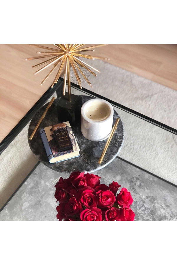 Round Black Marble Tray with Brass Handles in Living Room Setting, featuring a candle, small book, and metal flower home decor item.