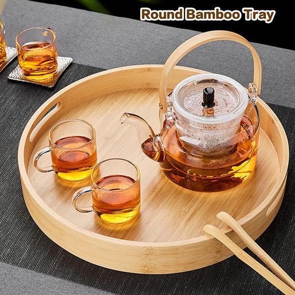 Round bamboo serving tray with handles, elegantly displayed with a glass teapot and a glass set.