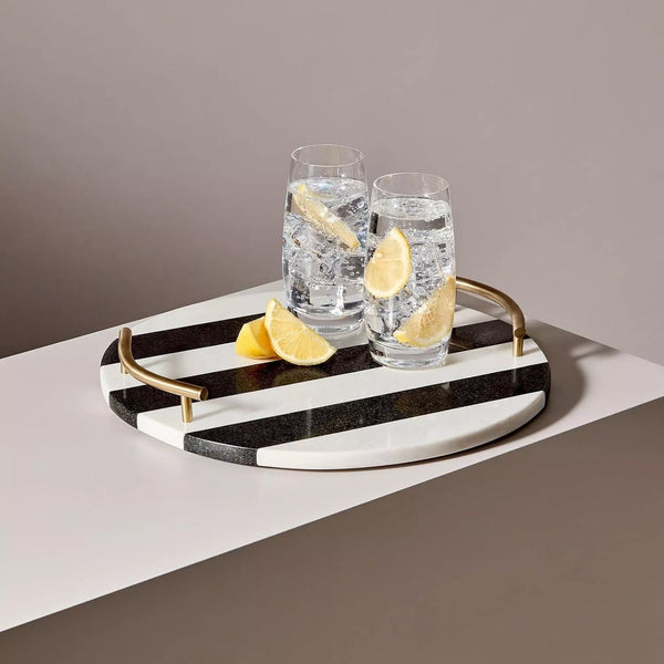 Round marble granite serving tray on tabletop with a glass filled with a white drink, showcasing elegant serveware.