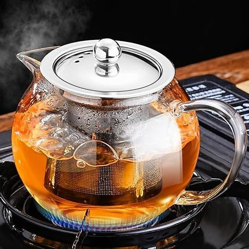 Slight top view of a glass teapot on a gas stove, cooking tea with visible steam.