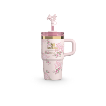 A white tumbler with a floral pattern, a pink lid, and a decorative element on the lid. 20oz