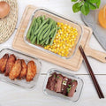 Three sizes of HaulJunction food containers, one filled with steaks, one with chicken wings, and one with fresh salad, all tightly sealed with airtight lids.