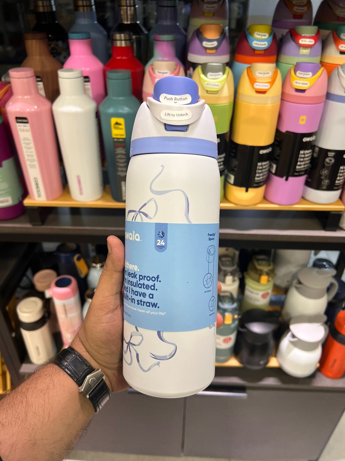 A hand holding a owala blue ribbon freesip 32oz water bottle showcasing live bottle 