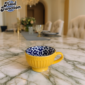 Yellow mug with blue and white patterned interior on a marble surface, blurred dining room background.