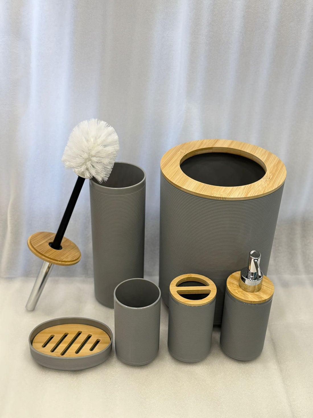 Bathroom accessories set with gray containers and wooden accents on a bathroom counter.