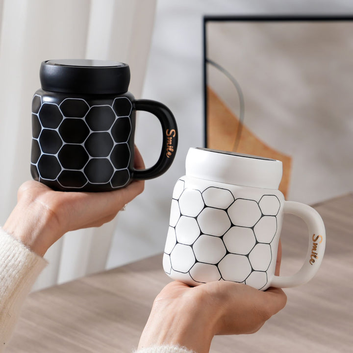 Showcasing a black and white smile mug held in hands with its unique honeycomb pattern visible.