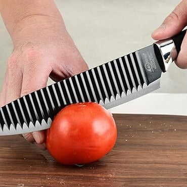 Large black knife cutting a tomato effortlessly, highlighting its sharp edge.