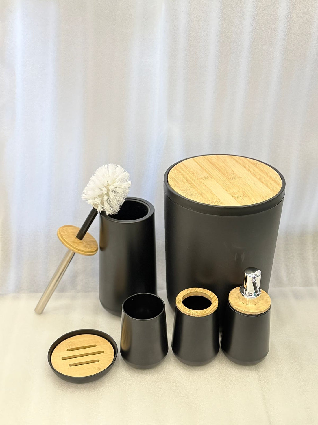 Black bathroom accessories set with wooden accents on a bathroom counter.