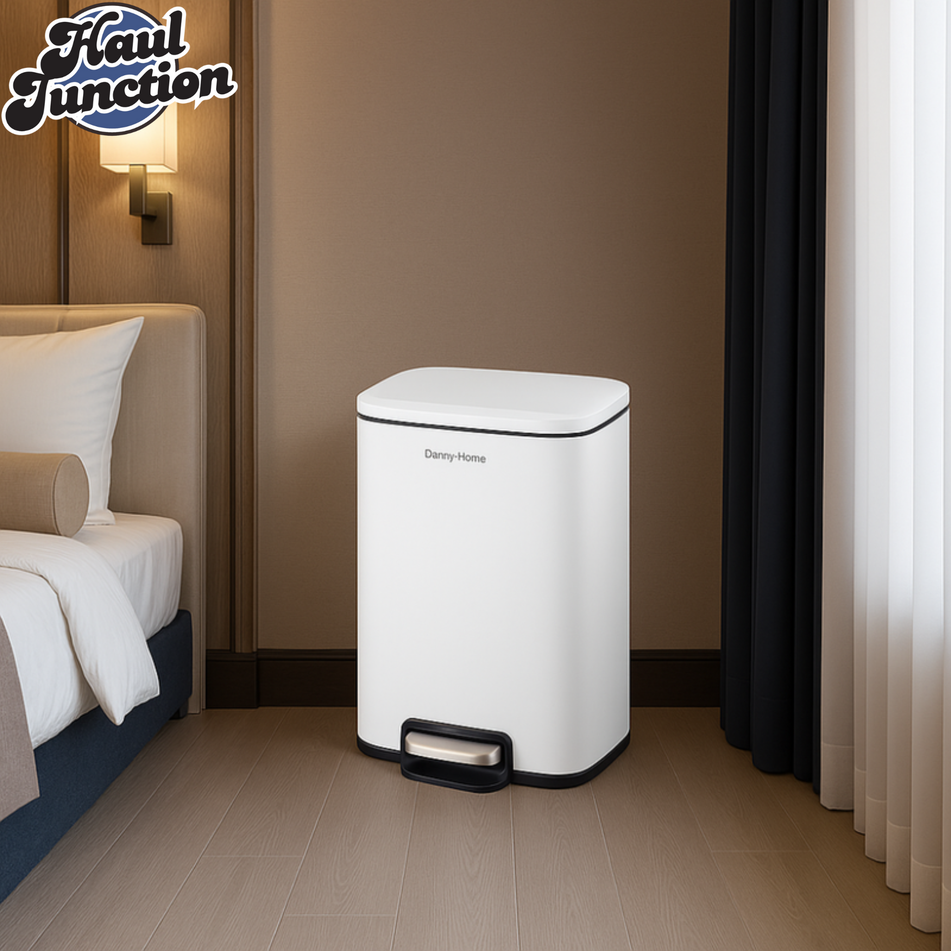 White trash bin in a bedroom setting with a bed and wall lamp in the background.