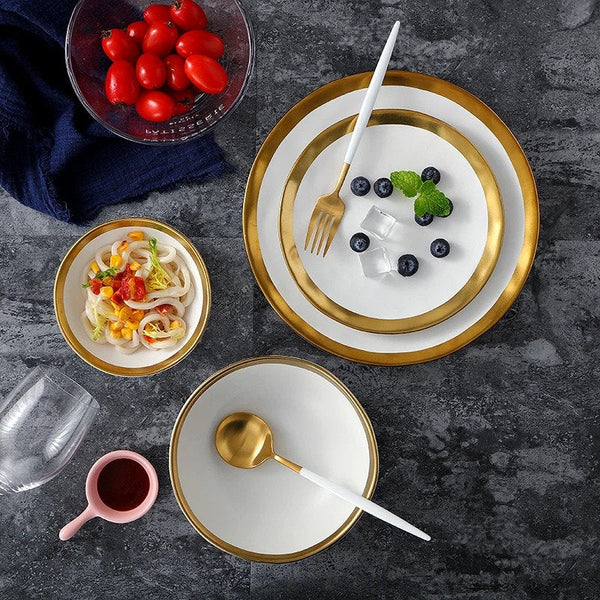 Top view of two plates, one large and one small, with a gold trim and white finish, accompanied by a small and large bowl, showcasing the elegant design.