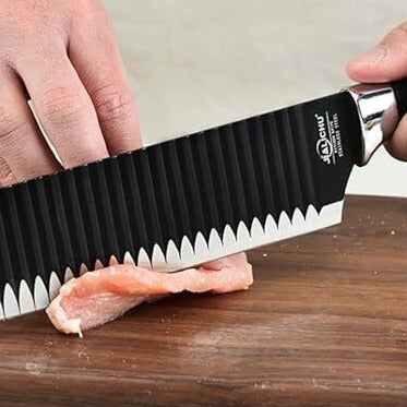 Large black knife slicing through a chicken breast, demonstrating its sharp precision.