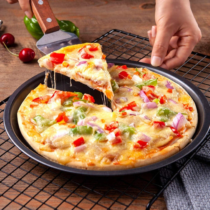 Close-up side view of a pizza slice being lifted with a spatula, showcasing the pan's non-stick surface.