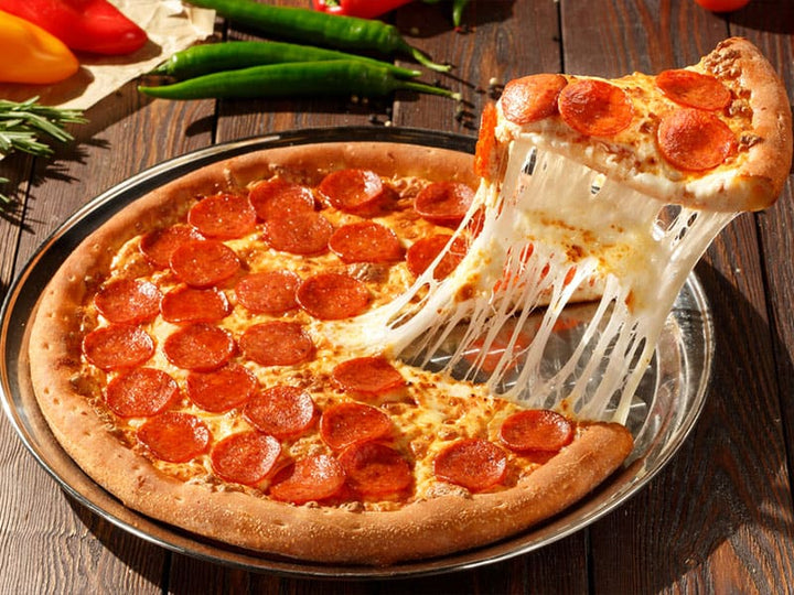 A slice of pizza being lifted from the non-stick pan, highlighting its effortless release.