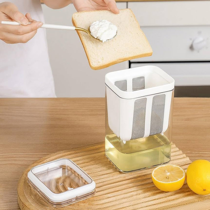 Person spreading greek youghurt on toast with a kitchen tool, surrounded by lemons and a container of honey.
