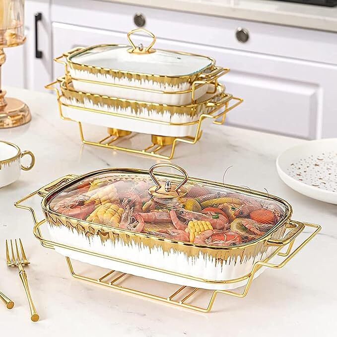 Showcasing a set of 3 food warmers with stand in white and gold, the large one filled with food inside.