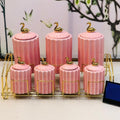 Slight top view of the 7-piece pink ceramic spice jar set with golden stand, highlighting the gold swan lid design.