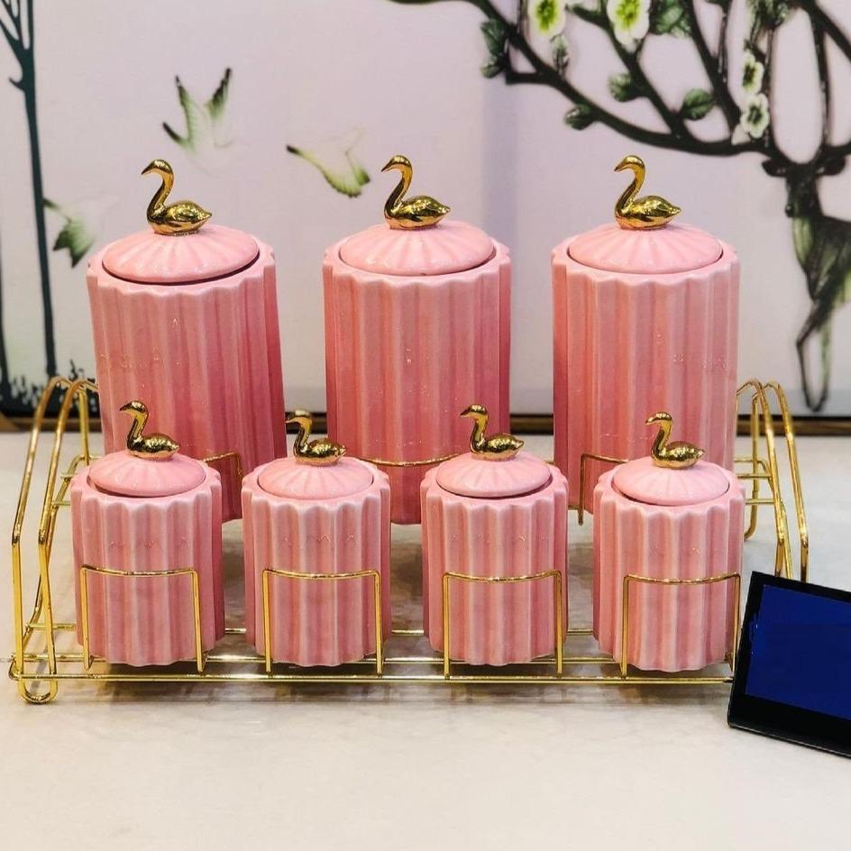 Slight top view of the 7-piece pink ceramic spice jar set with golden stand, highlighting the gold swan lid design.