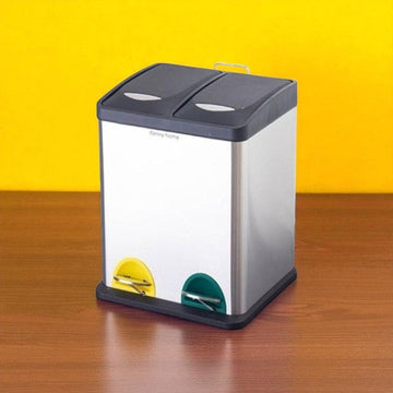 Two-compartment trash can on a wooden surface with a yellow background