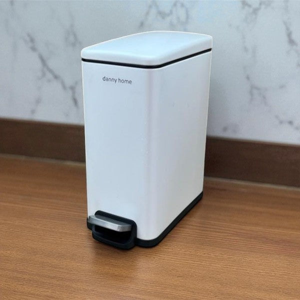 White trash bin with black accents on a wooden surface and marble wall background
