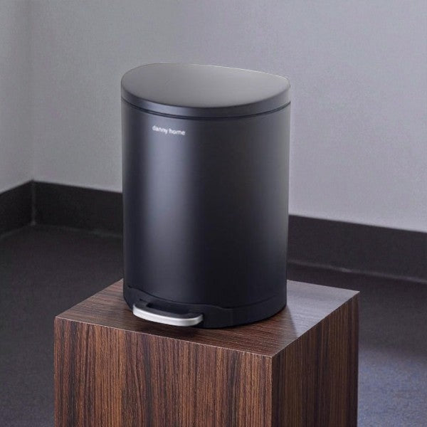 Black trash bin on a wooden pedestal against a gray wall