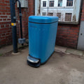 Blue trash bin against a brick wall